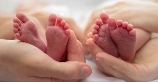 Twin baby feet in parents' hands