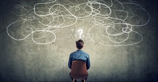 Man looking at twisted lines with question marks above his head