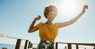 Joyful woman with arms raised at the beach