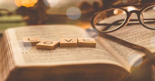 Scrabble tiles spelling "love" on top of an open Bible