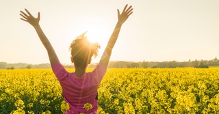 woman arms up in praise in wildflower field