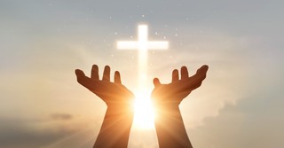 hands out and upward toward glowing cross in sky