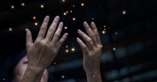 woman lifting hands up in worship with little lights sparkling