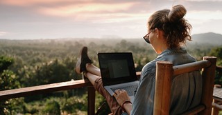 woman working on laptop overlooking a beautiful scenery outside