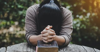 A woman earnestly praying over her Bible