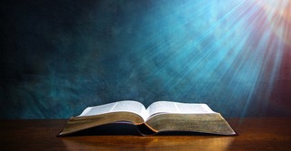open Bible on table with light shining down on it