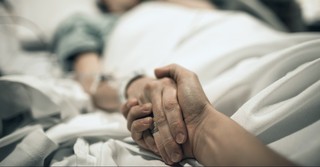 Hand holding on a hospital bed
