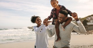 family laughing walking together on beach