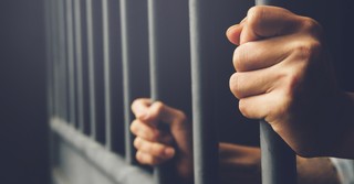 Person holding on to prison bars