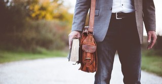 A pastor holding a shoulder bag and a Bible