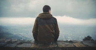 Back view of a man sitting on a wall