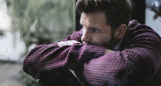 Sad man looking out a rainy window