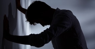 Sad man leaning against a wall