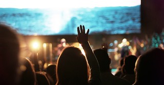 Woman in a worship service with hands raised