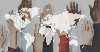 Multiracial hands raised over a map of the world