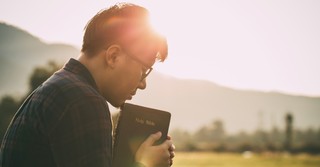 man holding a bible in a field