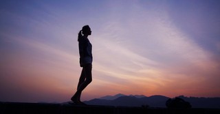 Silhouette of a woman standing, looking at the sunset