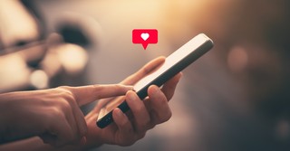 Finger pressing the like heart on a cell phone