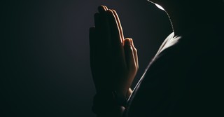 Praying hands in the dark