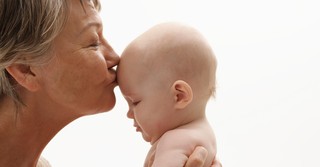 Grandmother kissing a baby on the forehead