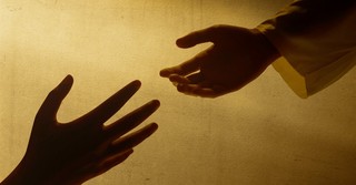 Silhouette of one hand reaching out to another for help