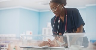 A nurse putting a baby in a hospital crib