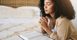 Woman praying, with Bible open