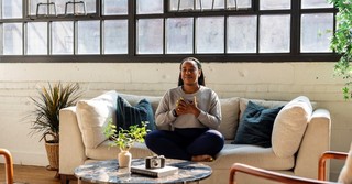 Woman sitting peacefully on a couch with her hands over her heart