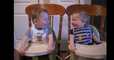 Twin Baby Boys Laugh At Each Other In Their Highchairs During Dinnertime