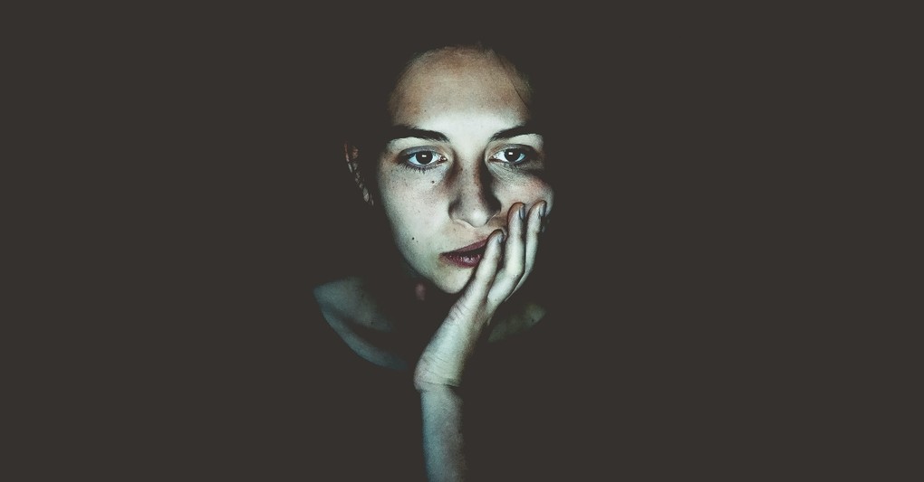 woman looking unsure or distressed in a dark space with electronic light on her face, habitual sins women struggle with