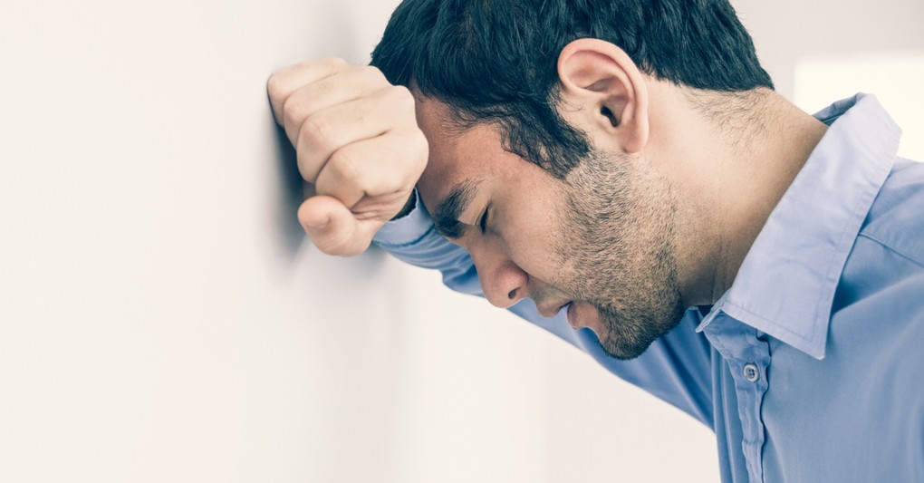 man concerned with head against wall in serious prayer to help my unbelief