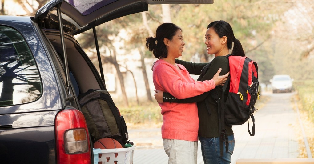 girl moving out of the house saying goodbye to mom at car