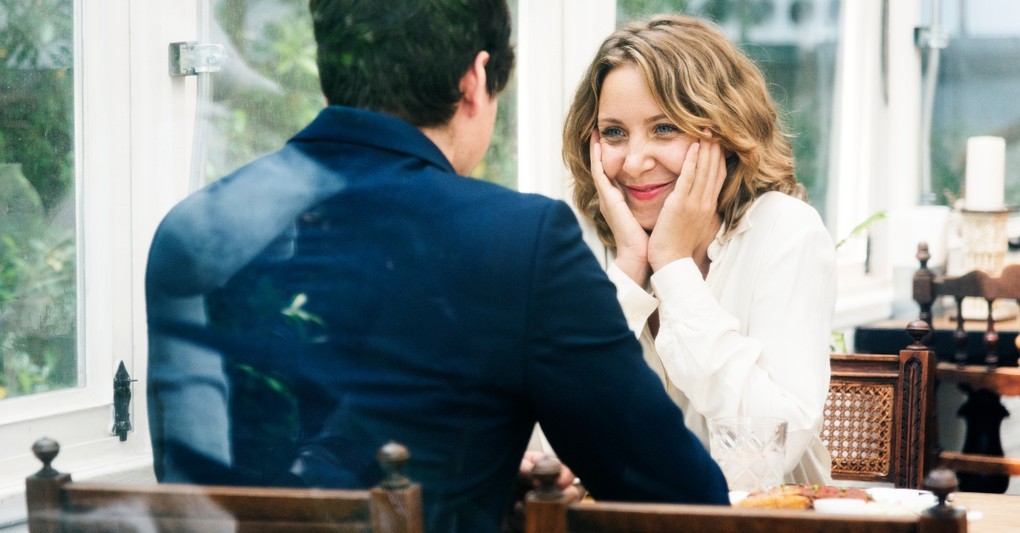 couple sitting at meal on date, woman looking smitten