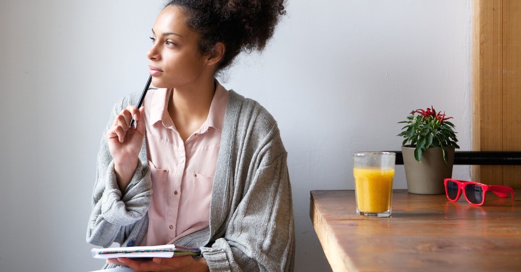 woman gazing out window morning journaling