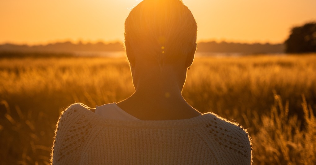 back of woman looking down in field, beautiful things god sees in you