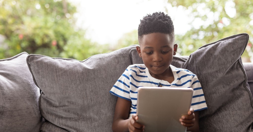 young boy sitting on couch reading ipad, teaching discernment to kids