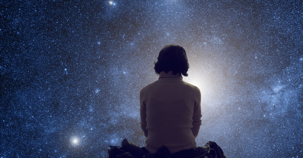 woman sitting looking at the night time sky stars