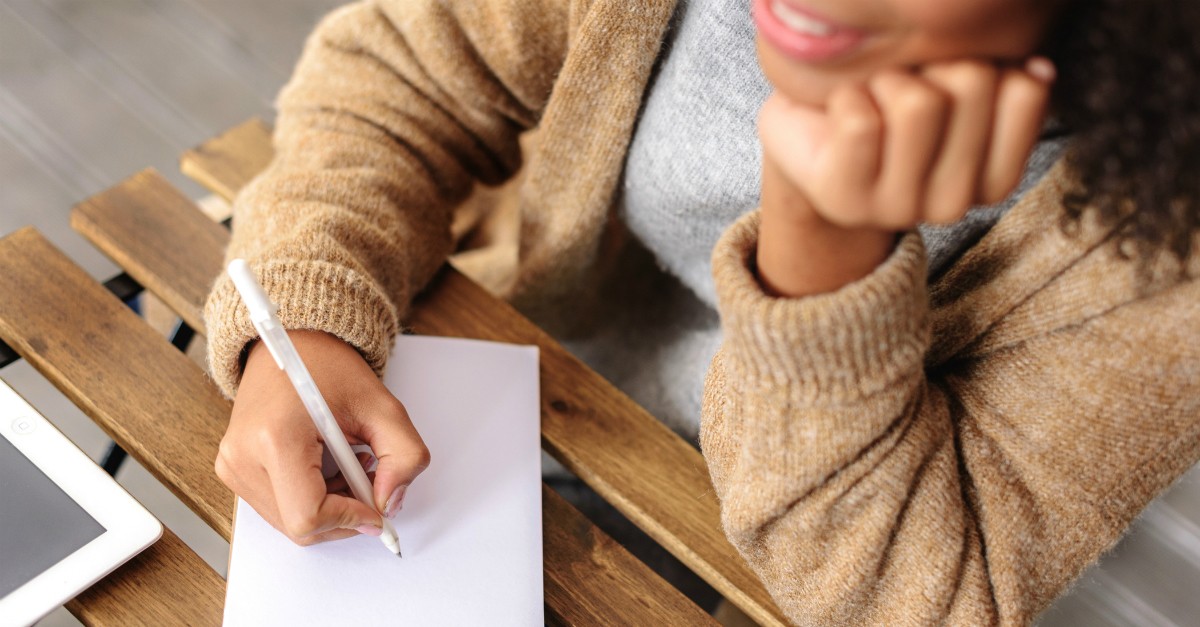 happy woman writing on piece of paper