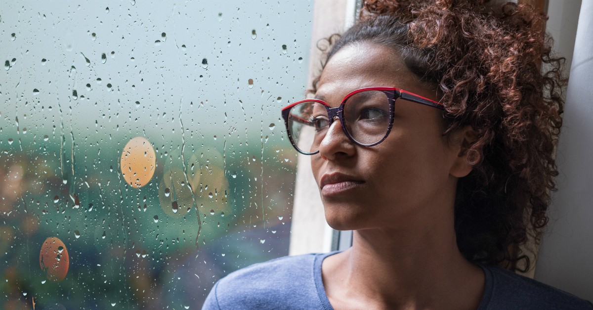 woman gazing thoughtfully out rainy window