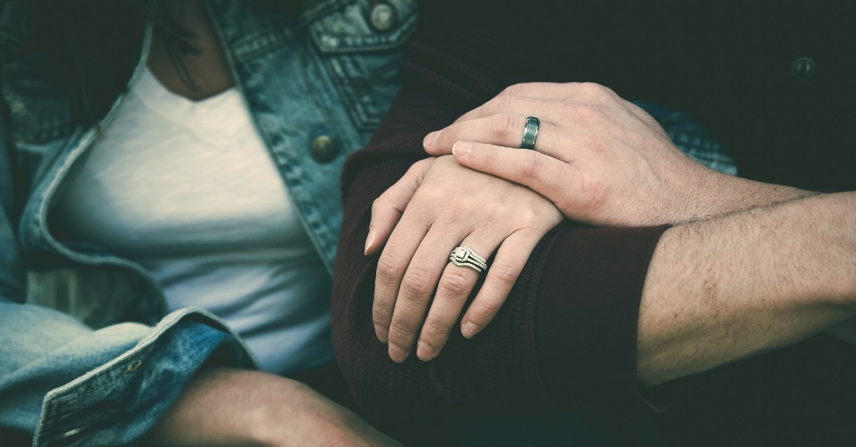 couple holding hands with wedding rings