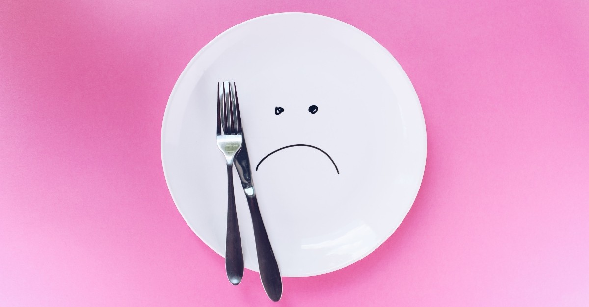 empty plate with sad face and fork and knife