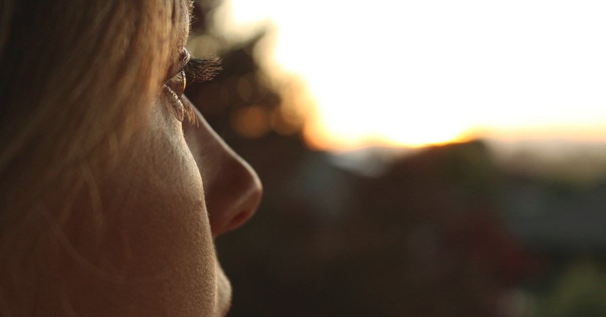 close up of woman gazing off into the middle distance sunset light, satisfied in god
