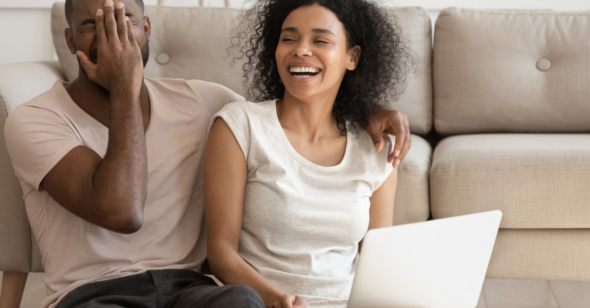 couple laughing at video on laptop computer