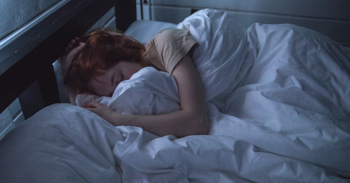 woman sleeping under puffy white comforter at night