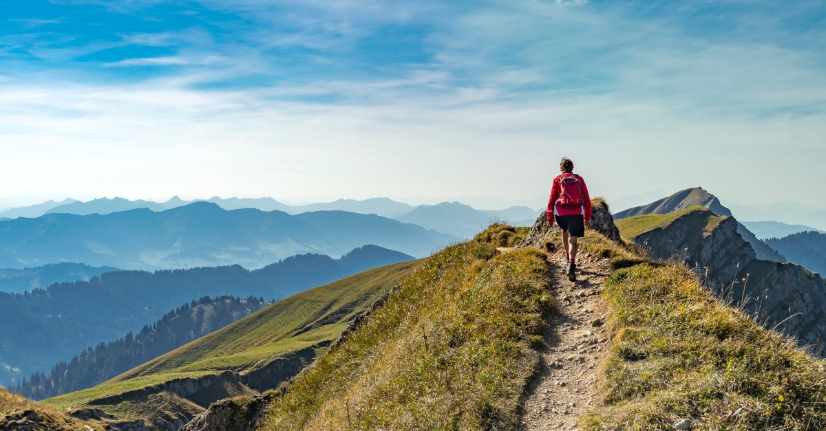 man hiking pathway to mountaintop nature