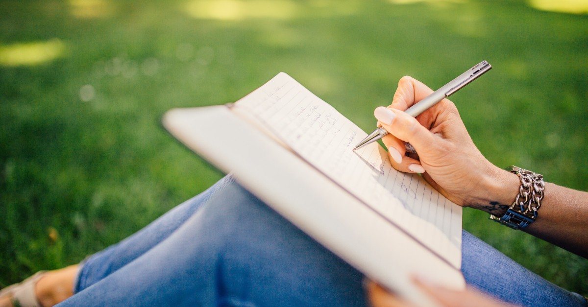 woman outdoors writing in gratitude journal
