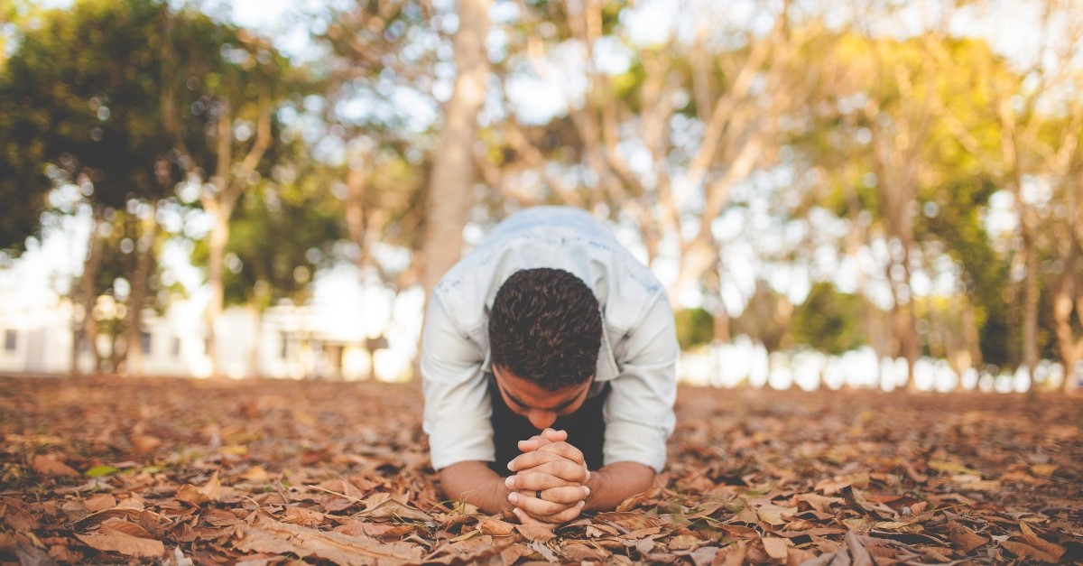 Man kneeling in the woods in prayer