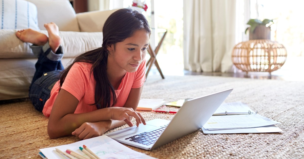 teenage girl working on homework and studying on living room floor, teach teens true definition of success