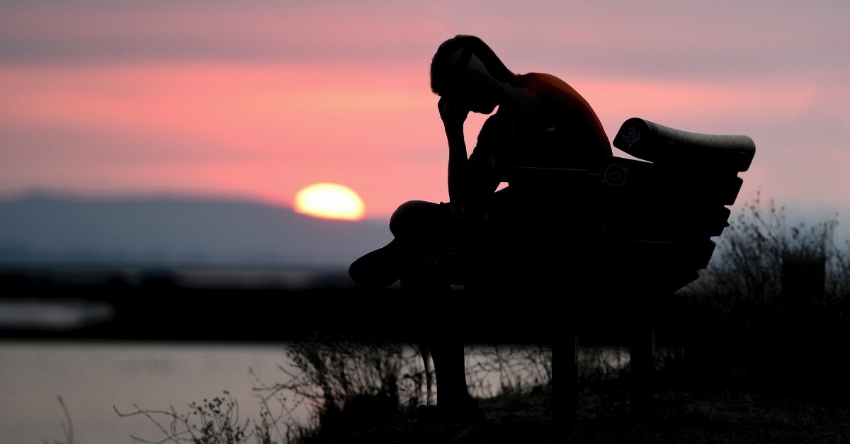 young person sitting on a bench at sunset looking tired and discouraged, prayer when faith is tired