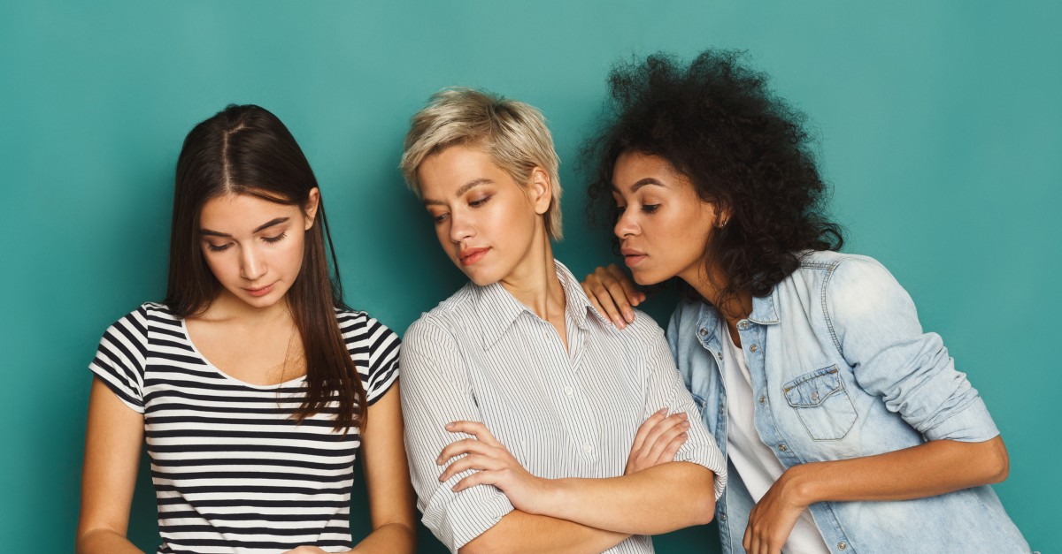 three women friends looking at cell phone together serious